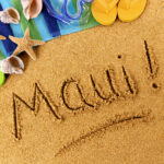 The word "Maui" written on sand.